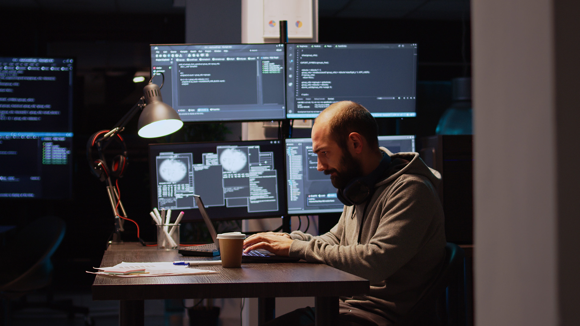 Man sitting at computer in front of multiple screens.