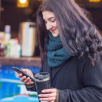 Woman holding phone and cup in a market