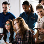 A group of collegues standing around a computer collaborating